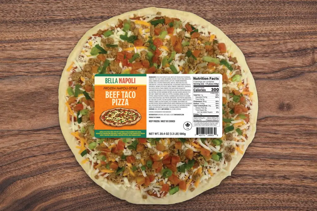 A top down photo of a frozen Beef Taco pizza on a wood background. The pizza is wrapped in plastic and has the Bella Napoli label on the front.