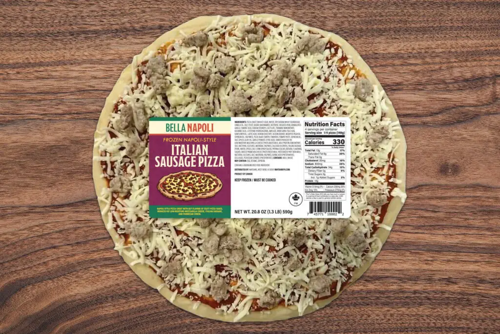 A top down photo of a frozen Italian Sausage pizza on a wood background. The pizza is wrapped in plastic and has the Bella Napoli label on the front.