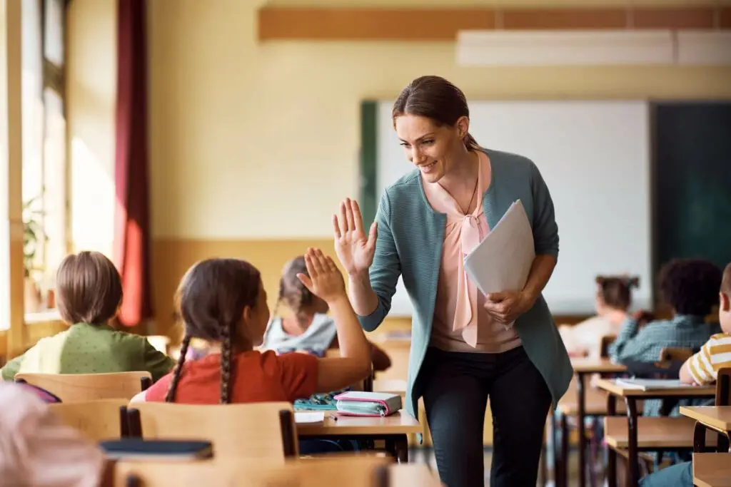 Teacher high-fiving a girl in her classroom